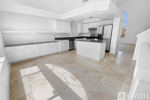 A spacious kitchen with white cabinets and a tiled floor.