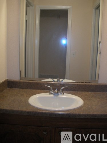 A bathroom sink with a brown counter top and a mirror above it.