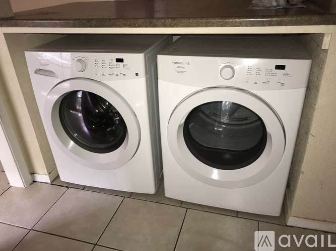 Two white front load washing machines in a laundry room.