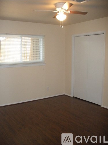 A room with a ceiling fan and a window with blinds.