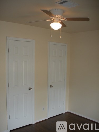 A room with a ceiling fan and two doors.