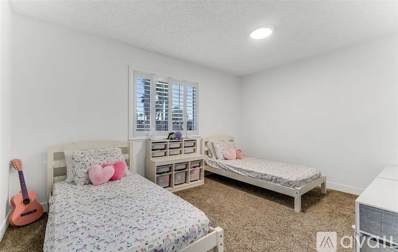A bedroom with two beds, a dresser, and a guitar.