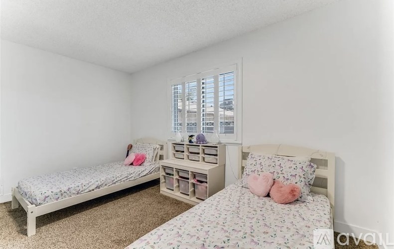 A bedroom with two beds and a nightstand.