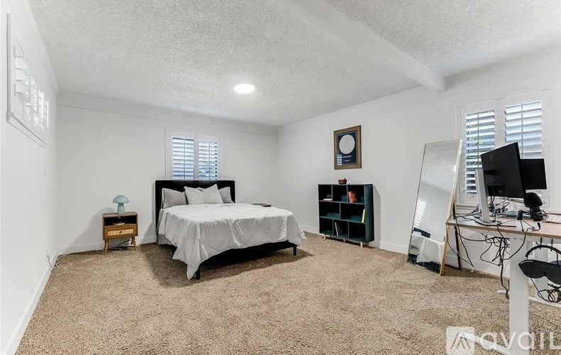 A bedroom with a bed, desk, and chair.