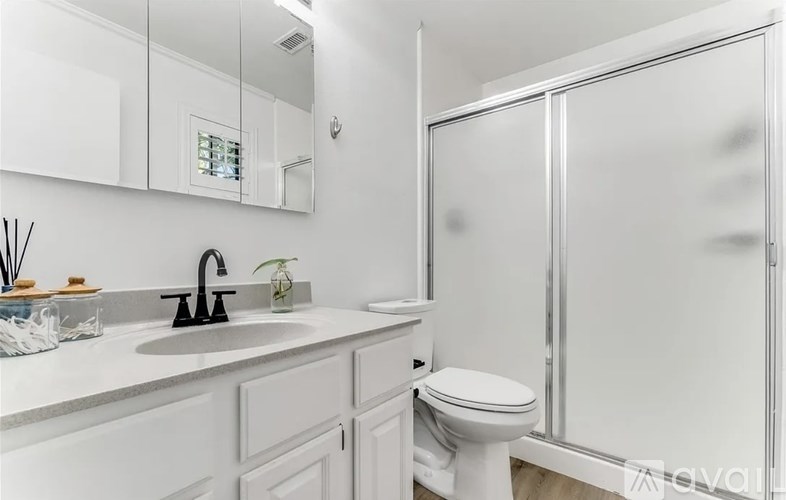 A white bathroom with a sink, toilet, and shower.