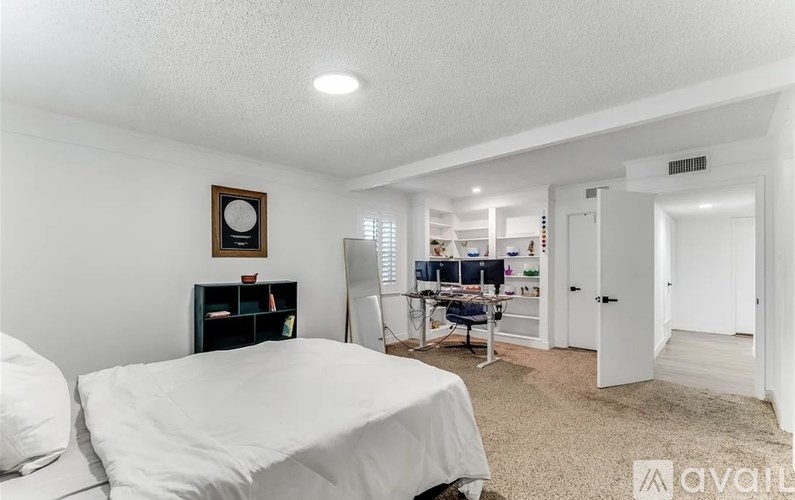 A bedroom with a bed, desk, and chair.