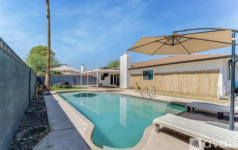 A pool with a bench and umbrella next to a house.