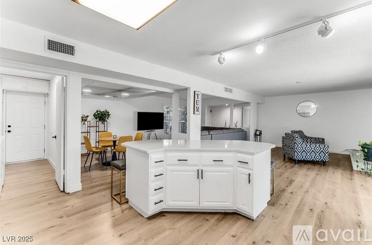 A modern kitchen with white cabinets and a wooden floor.