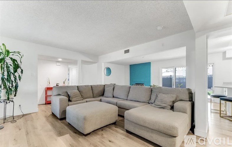 A living room with a grey sectional sofa and a green plant.