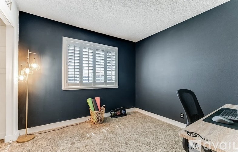A room with a window, a chair, a table, and a floor lamp.