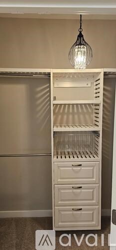 A white cabinet with a hanging light fixture above it.