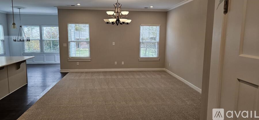 A spacious room with a carpeted floor and a chandelier hanging from the ceiling.