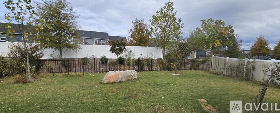 A backyard with a large rock in the center and a fence surrounding it.