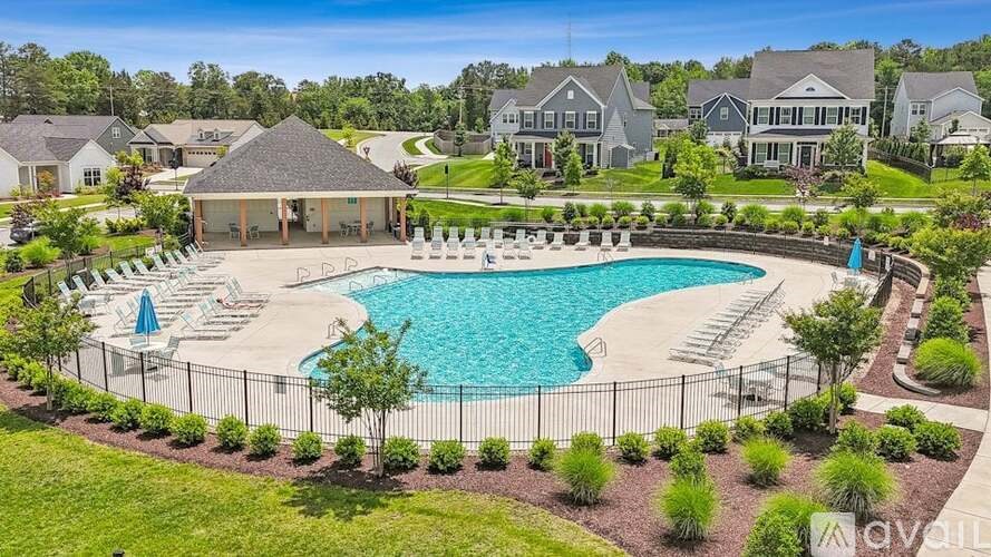 A large swimming pool surrounded by a black fence and lounge chairs.