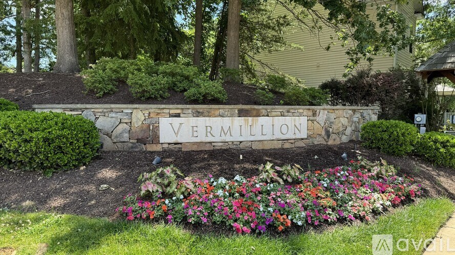 A garden with a stone sign that says "Vermillion" in front of a house.