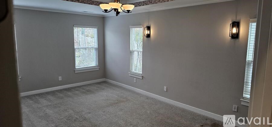 A room with a chandelier, two windows, and wall sconces.