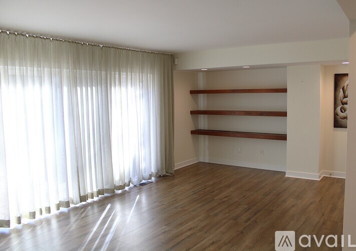 A room with wooden floors and a window with curtains.