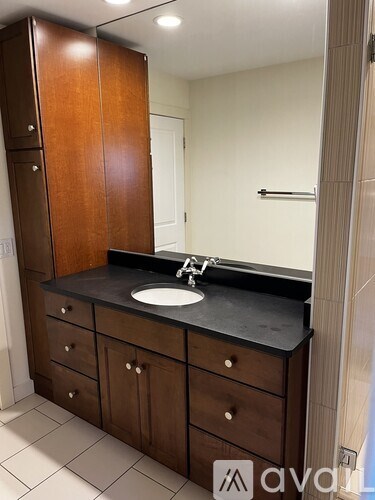 A bathroom with a sink, mirror, and wooden cabinets.