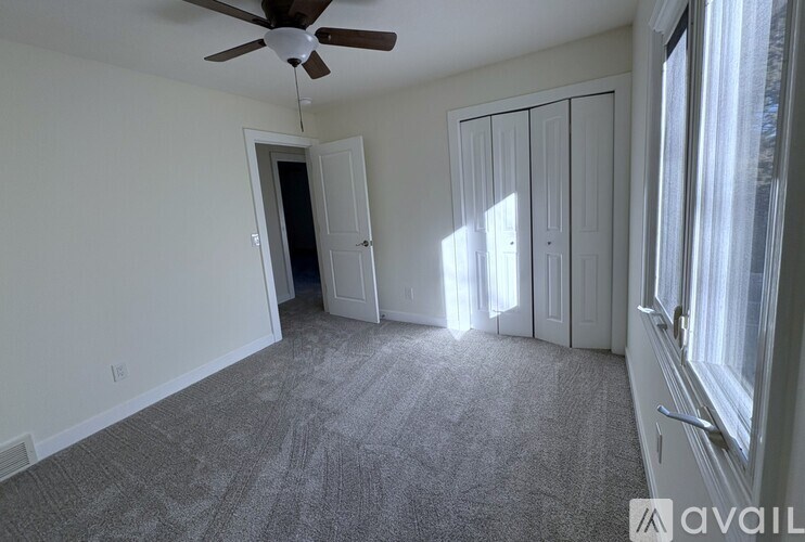 A room with a ceiling fan and carpeted floor.