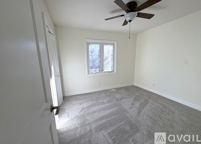 A room with a ceiling fan and a window.