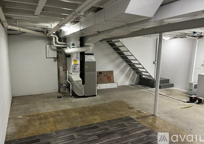 A large industrial room with a staircase, pipes, and a machine.