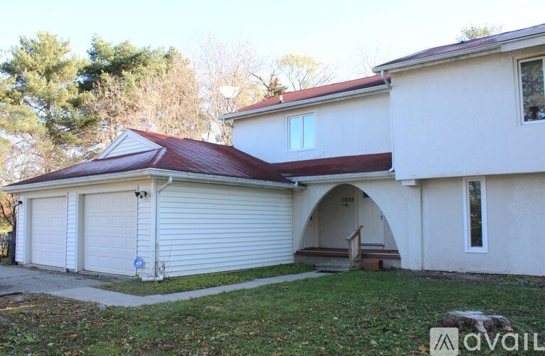 A two-story house with a red roof and a white garage door.