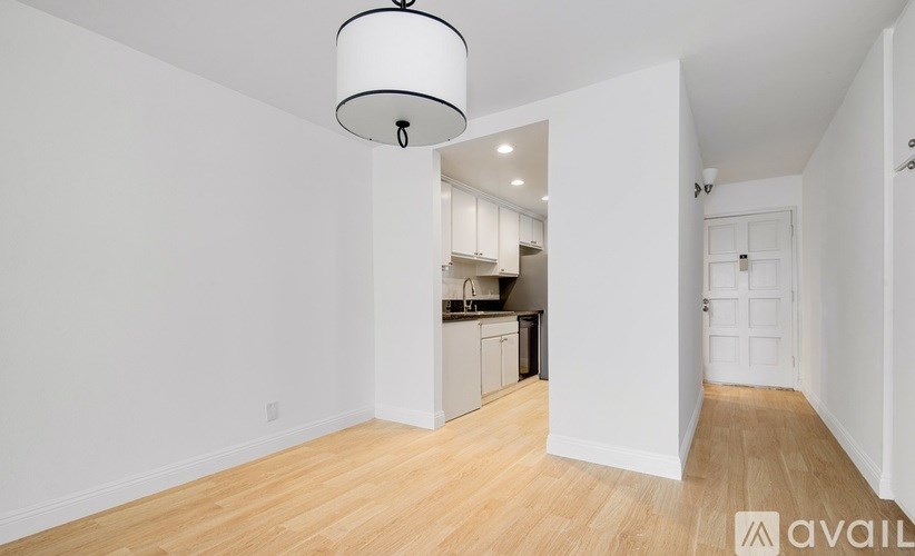 A white room with a wooden floor and a hanging light fixture.