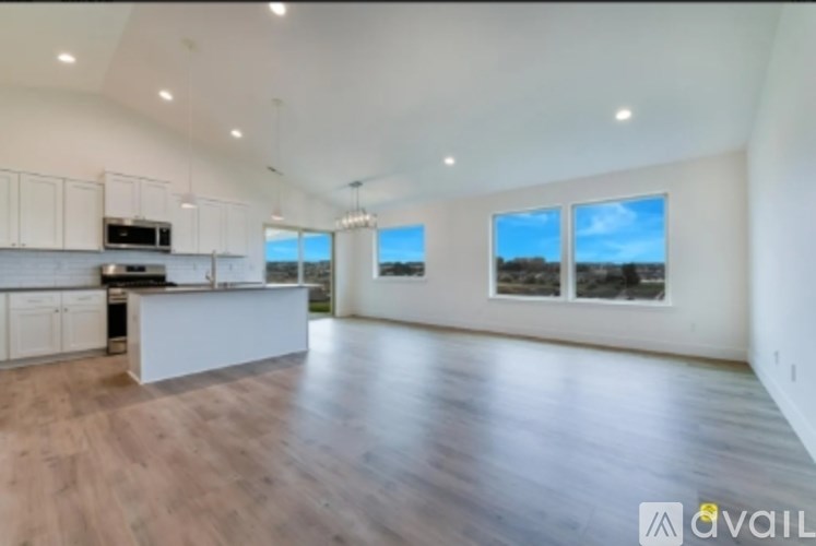 A spacious living room with wooden floors and large windows.