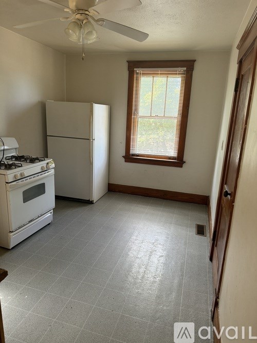 A kitchen with a white refrigerator, a white stove, and a ceiling fan.