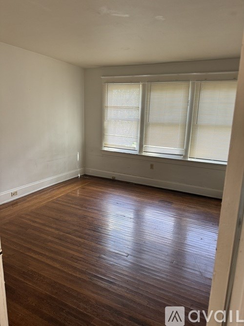 A room with wooden flooring and a window with blinds.