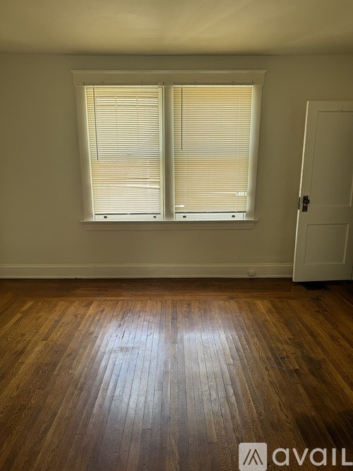 A room with wooden flooring and a window with blinds.
