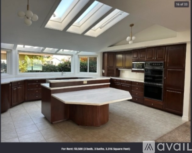 A kitchen with brown cabinets and a skylight.