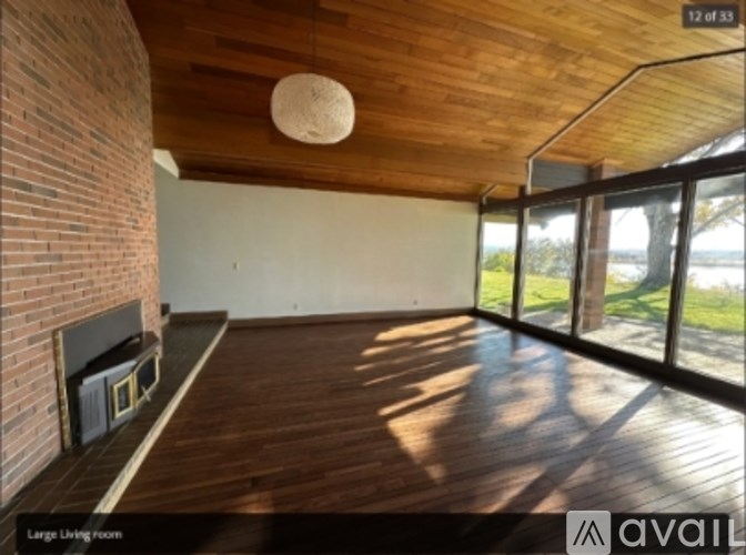 A large living room with wooden floors and a brick wall.