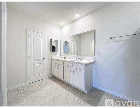 A bathroom with a white door, sink, and mirror.