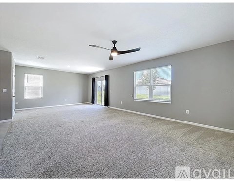 A spacious room with a ceiling fan and carpeted floor.