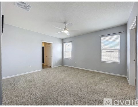 A room with a carpeted floor, a ceiling fan, and a window with blinds.