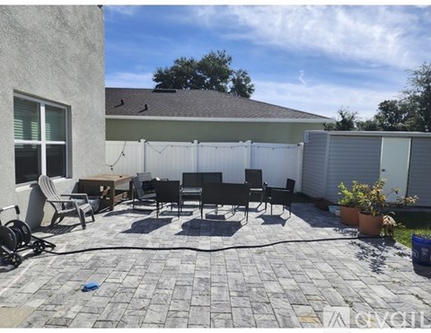 A patio with a table and chairs is surrounded by a white fence.