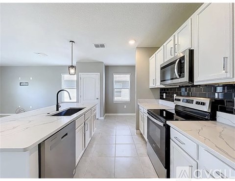 A kitchen with white cabinets and a black microwave.