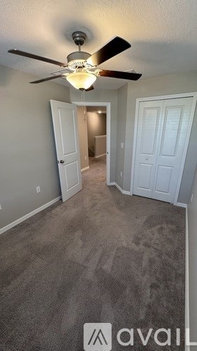 A room with a ceiling fan and carpeted floor.