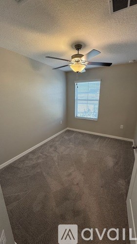 A room with a ceiling fan and carpeted floor.
