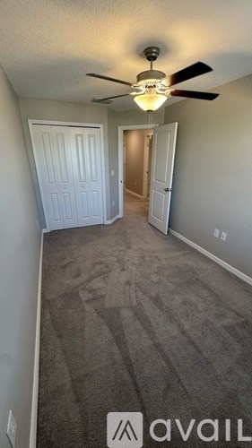 A room with a carpeted floor and a ceiling fan.