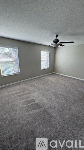 A room with a carpeted floor and a ceiling fan.