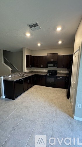 A kitchen with dark brown cabinets and a black stove top oven.
