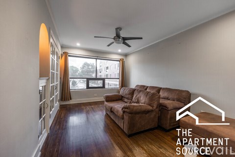 A living room with a brown leather couch and a ceiling fan.