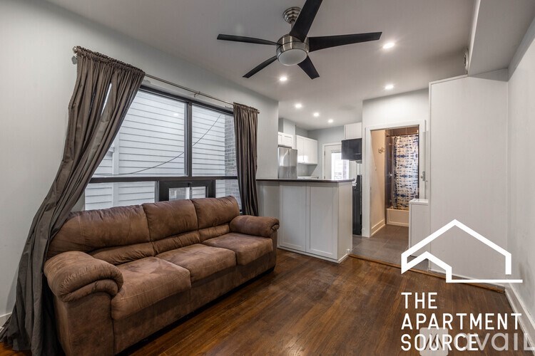 A living room with a brown couch and a ceiling fan.