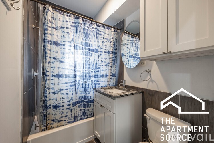A small bathroom with a shower curtain and a washing machine.
