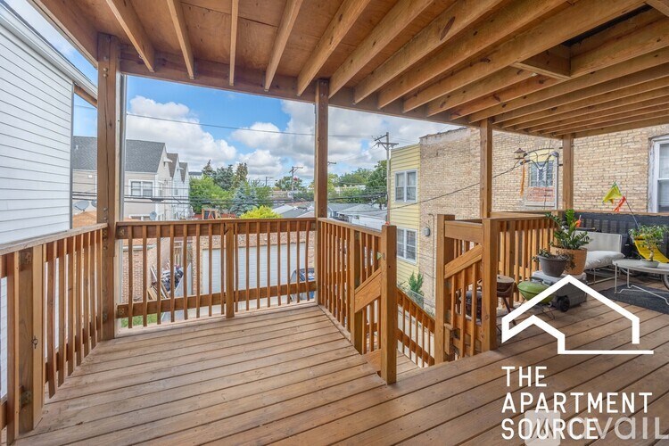 A wooden deck with a railing and a table with chairs on it.