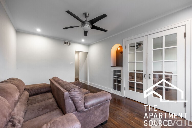 A brown leather couch in a room with a ceiling fan.