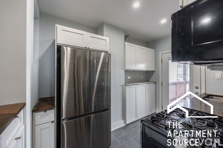 A modern kitchen with a stainless steel refrigerator and white cabinets.