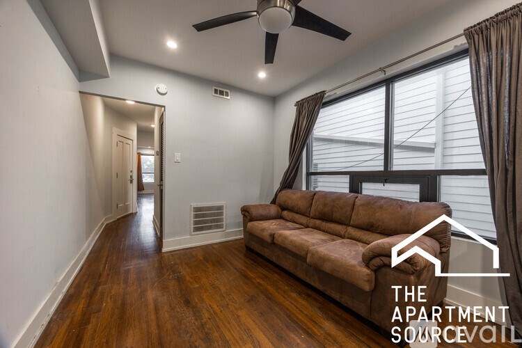 A living room with a brown couch and a ceiling fan.